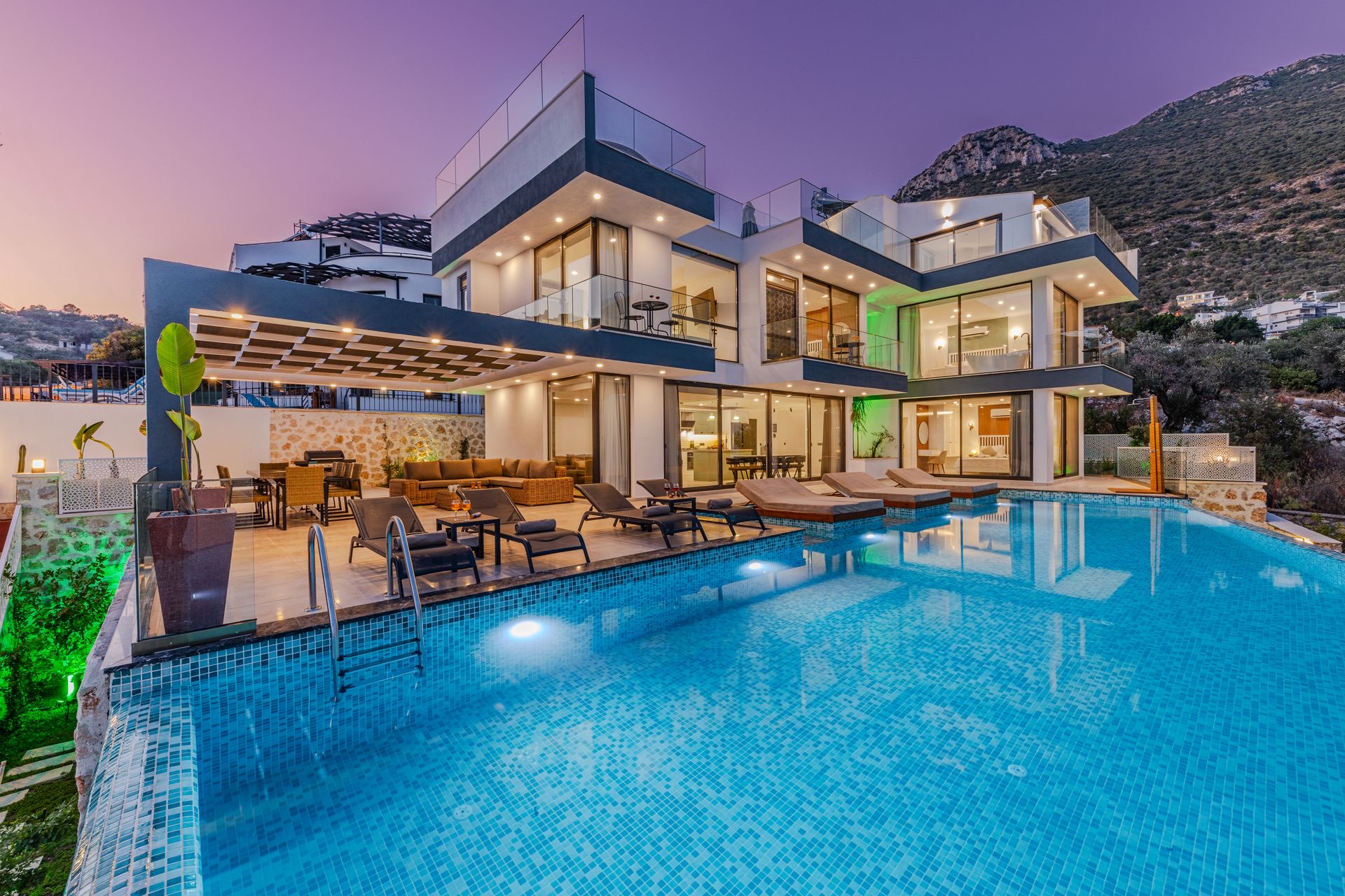 Swimming pool at a hillside home with mountains behind at dusk